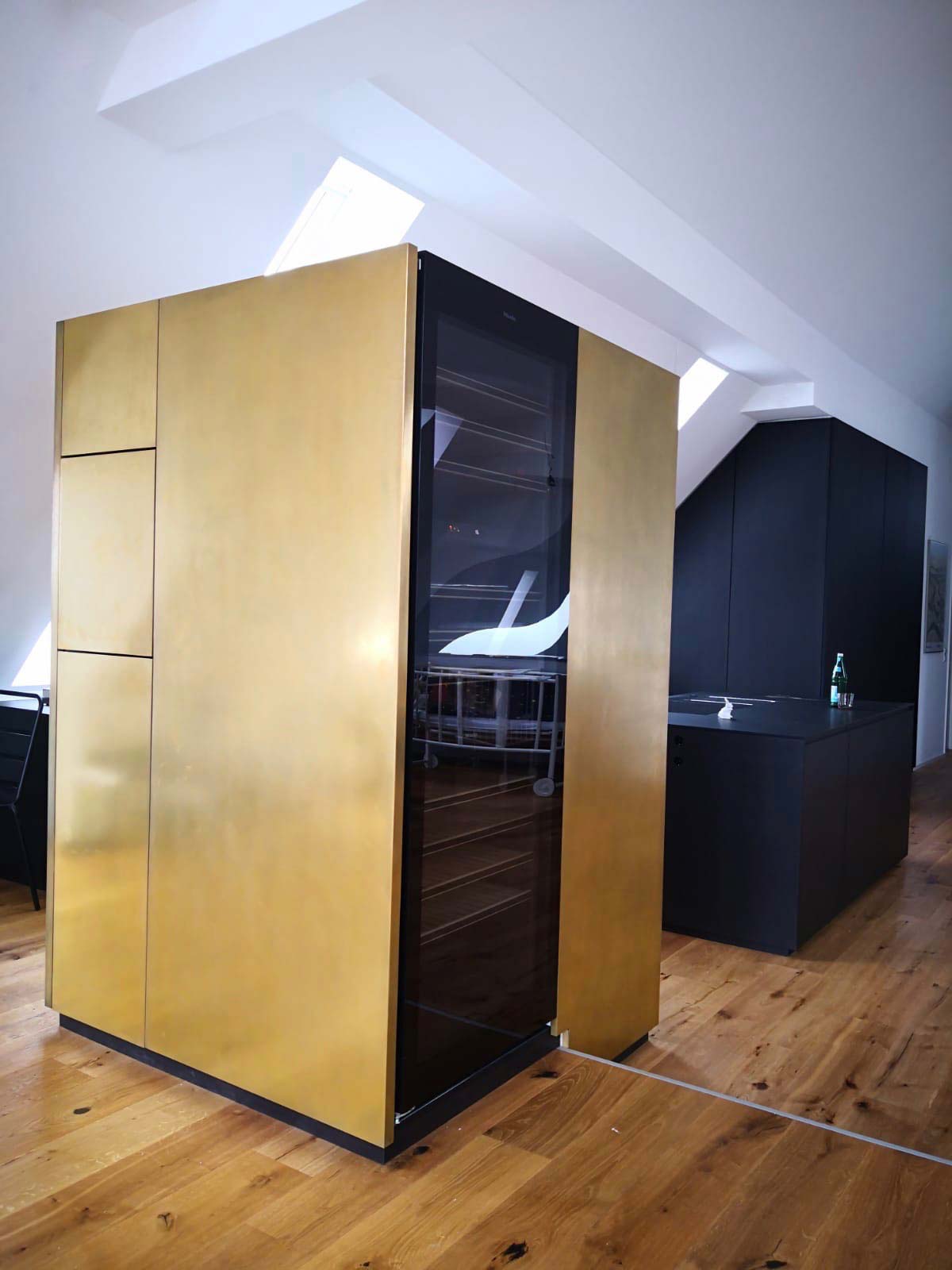 Schwarze Küche mit Kühlschrank-Element in goldenem Metalllack